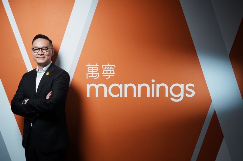 Executive portrait of a Mannings leader in front of the brand wall